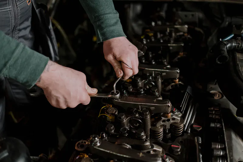 Mechanic's hands working a wrench on an engine valve train