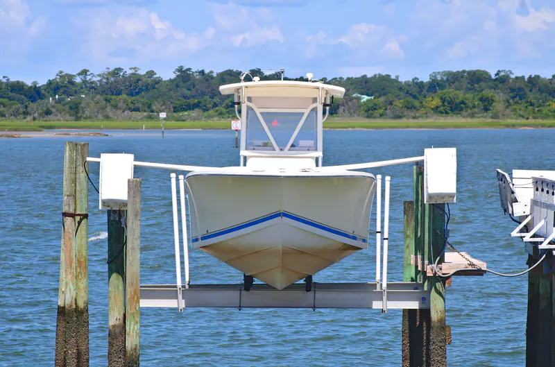 Center-console boat raised on a dock lift over the water